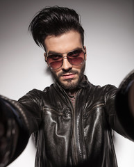 Obraz premium handsome fashion man holding the camera with his hands