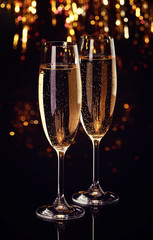 Two flutes of champagne on dark bokeh background