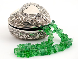 Casket with emerald necklace on a white background