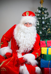 Santa Claus with gifts near the Christmas tree.