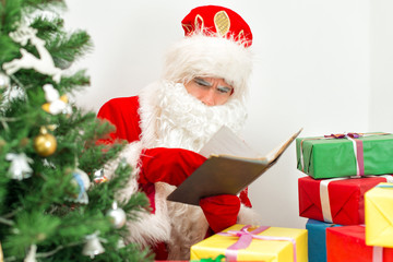 Santa Claus checking wish list at his workshop.