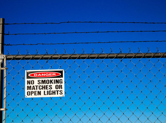 Danger Sign on Chain Link Fence with Barbed Wire