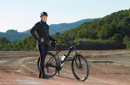 Cyclist standing with mountain bike in nature