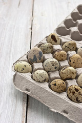 Quail eggs in the cardboard packing on the white table