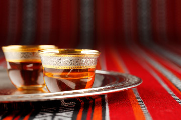 A tray of Arabian tea cups is placed on Arabian woven fabric