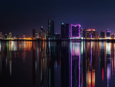 Night modern city skyline with neon lights and reflections