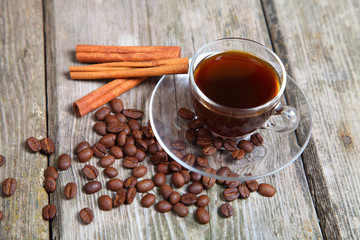 Transparent cup of coffee, beans and cinnamon sticks