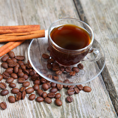 Transparent cup of coffee, beans and cinnamon sticks