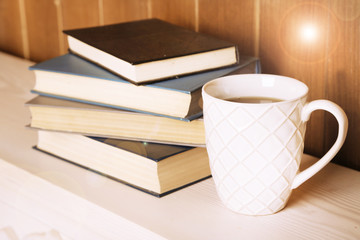 Old books and cup of coffee on table