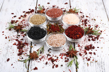 Spices in glass round bowls with herbs on wooden background