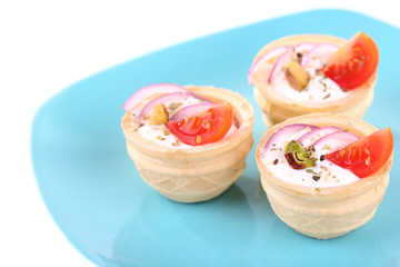 Tartlets with greens and vegetables with sauce on plate