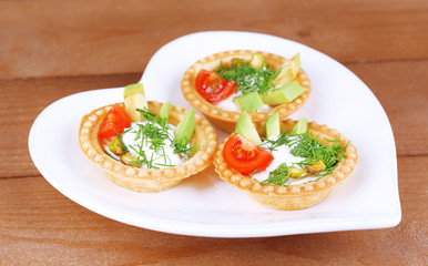 Tartlets with greens and vegetables with sauce on plate on