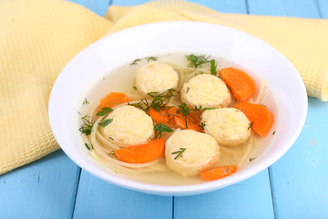 Soup with meatballs and noodles in bowl on wooden background