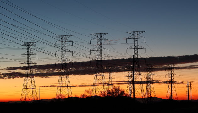 High voltage energy transformers with orange, yellow sky sunset