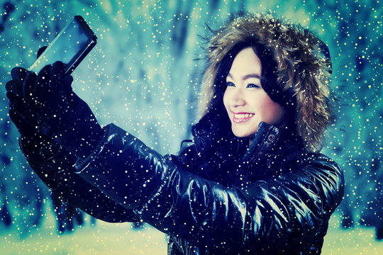 Girl in winter jacket taking self portrait