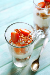 Healthy layered dessert with muesli and strawberries on table