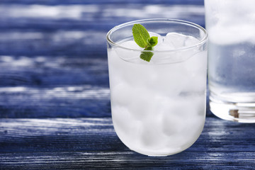 Glass with ice cubes on wooden table