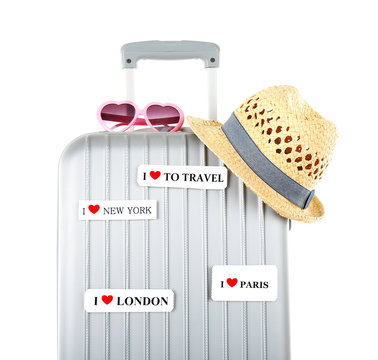 Travel suitcase, sunglasses and hat isolated on white