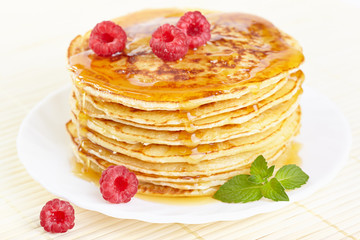 Pancakes with honey, raspberry and a mint branch