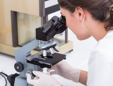 female student looking into the microscope