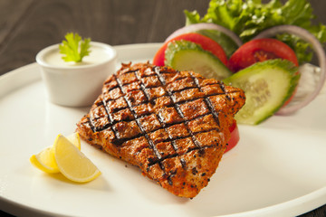 Grilled fish tikka served on a plate with salad and tarter sauce