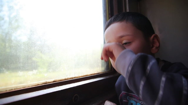 little boy traveling in a train and looking through window