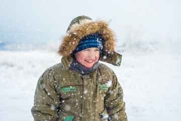 Fototapeta na wymiar Portrait of a smiling little boy with falling snow