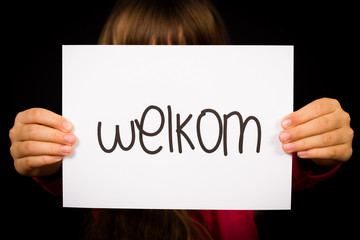 Child holding sign with Dutch word Welkom - Welcome
