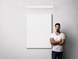 Bearded man and white blank poster on a wall