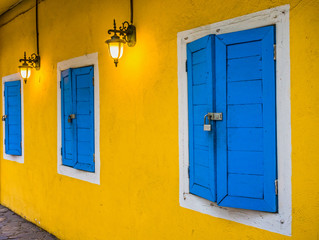 The wall lamp and locked blue windows of yellow house