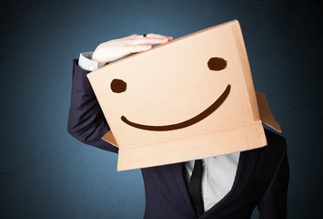 Businessman gesturing with a cardboard box on his head with smil