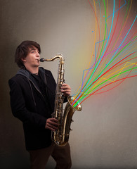 Fototapeta na wymiar Attractive musician playing on saxophone while colorful abstract