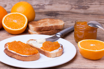 slices of bread with butter and orange jam on white plate.