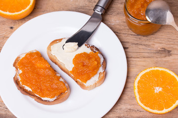 slices of bread with butter and orange jam on white plate.