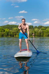Young attractive man on stand up paddle board in the lake, SUP