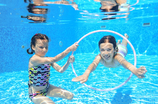 Kids swim in pool underwater, children on vacation