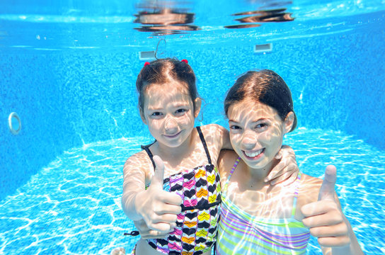 Kids swim in pool underwater, children on vacation