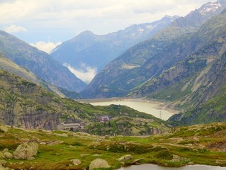 Footpath at stony meadow above deep misty valley in Alps.