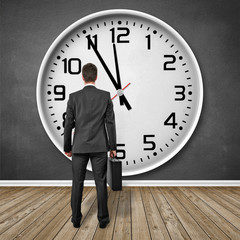 Mann steht vor einer Uhr!