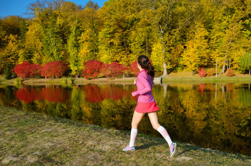 Woman running in autumn park, girl runner jogging outdoors
