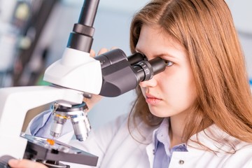 Scientist young woman using a microscope in a science laboratory