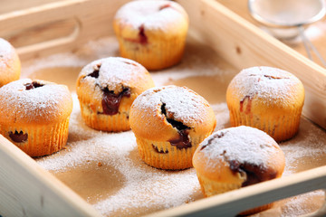 Muffins with jam sprinkled with powdered sugar on wooden tray