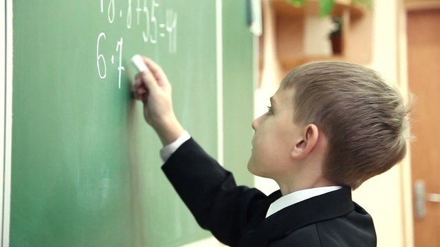 little boy solves math on the blackboard at school 7