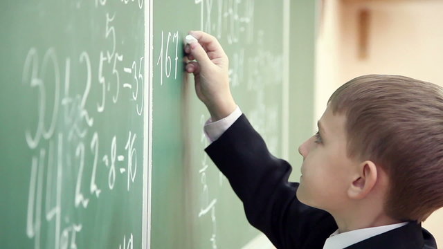 little boy solves math on the blackboard at school 2