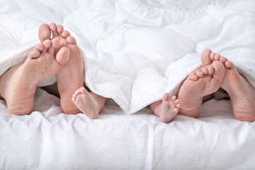 Funny family feet under the white blanket