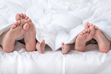 Couple with baby showing foot under the blanket
