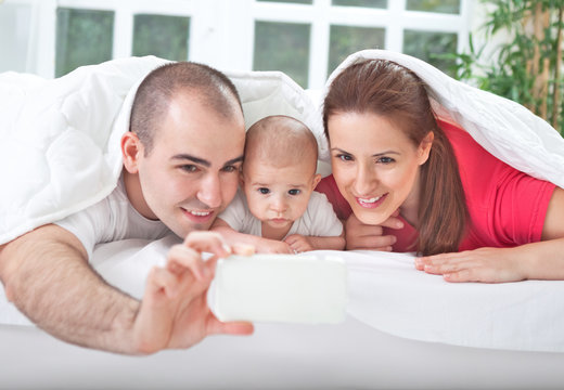 Smiling parents with baby taking family photo