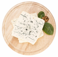 blue cheese decorated with arugula and walnut on wooden board is