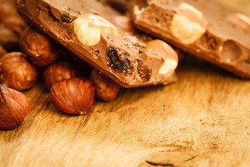 Milk chocolate and hazelnuts on wooden table