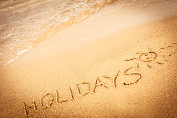 The word holidays written in the sand on a beach